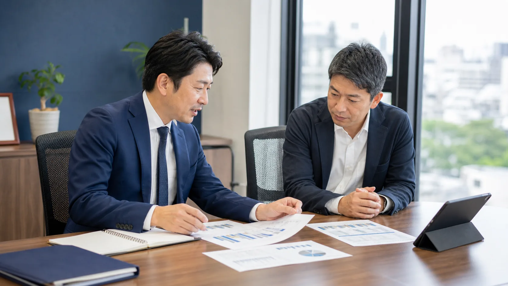 経営資料を確認しながら会社売却を相談する経営者と専門家